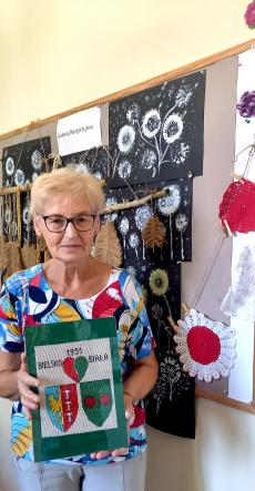 Powiększ zdjęcie: Pani Jadwiga trzyma w ręku własnoręcznie wyhaftowaną pracę przedstawiającą herb Bielska-Białej