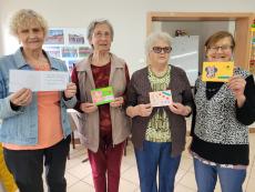 Powiększ zdjęcie: Seniorki trzymające w rękach kartki własnoręcznie wykonane dla dzieci.