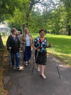 Powiększ zdjęcie: Seniorzy z Dziennego Domu Senior Plus na spacerze w parku Adama Mickiewicza podczas zajęć z nordic-walking