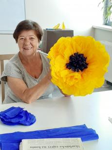 Powiększ zdjęcie: Uczestniczka Klubu Senior Plus z ulicy Jutrzenki podczas zajęć manualnych wykonuje żółty kwiat z bibuły