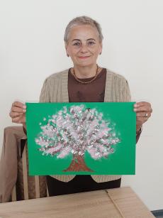 Powiększ zdjęcie: Uczestniczka Klubu Senior Plus z ulicy Jutrzenki z własnoręcznie wykonaną pracą przedstawiającą drzewo