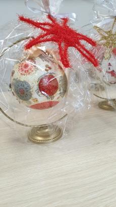 Powiększ zdjęcie: Zdjęcie przedstawia bombkę świąteczną zapakowaną w folię z czerwona gwiazdą