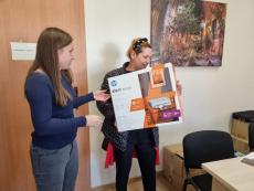 Powiększ zdjęcie: Zdjęcie przedstawia dwie kobiety, jedna z nich trzyma pudełko z drukarką