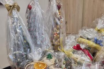 Zdjęcie przedstawia kilka prezentów zapakowanych w przezroczysta folię, zawiązanych ozdobnymi wstążkami i udekorowanymi suszonymi plastrami pomarańczy.